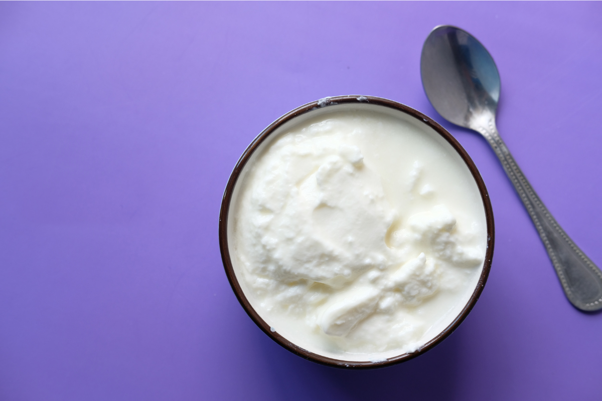 jogurt naturalny z malinami miseczka z jogurtem naturalnym obok świeżych malin i łyżki