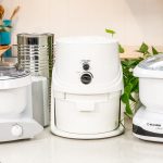 Srebrny robot kuchenny Magimix z widocznym czarnym silnikiem na białym blacie kuchennym