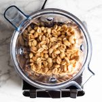 Blender stołowy z prażonymi orzechami ziemnymi obok słoika gładkiego masła orzechowego