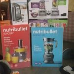 Czerwony blender Nutri Bullet z kubkami smoothie i akcesoriami na stole