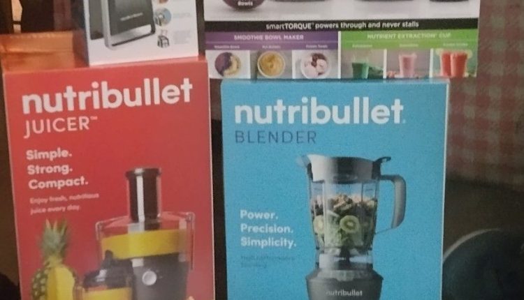 Czerwony blender Nutri Bullet z kubkami smoothie i akcesoriami na stole