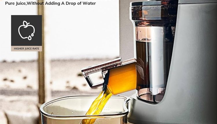 Srebrna wyciskarka 4Swiss z szerokim wlotem stoi na białym tle obok szklanki soku