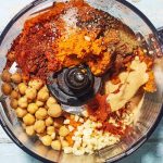 kremowy hummus w misce z oliwą, ciecierzycą i płaskim chlebem na stole