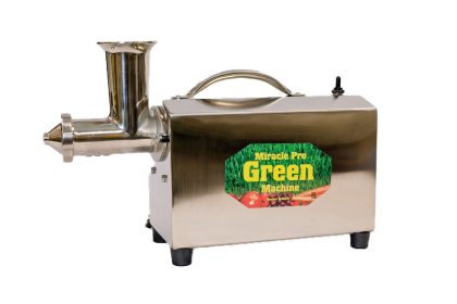 zielona wyciskarka do soku z trawą pszeniczną i szklanką świeżego napoju obok