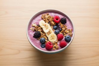 szklanka zielonego smoothie z bananami jagodami i erytrytolem obok blendera