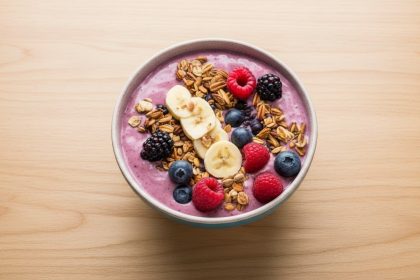 szklanka zielonego smoothie z bananami jagodami i erytrytolem obok blendera